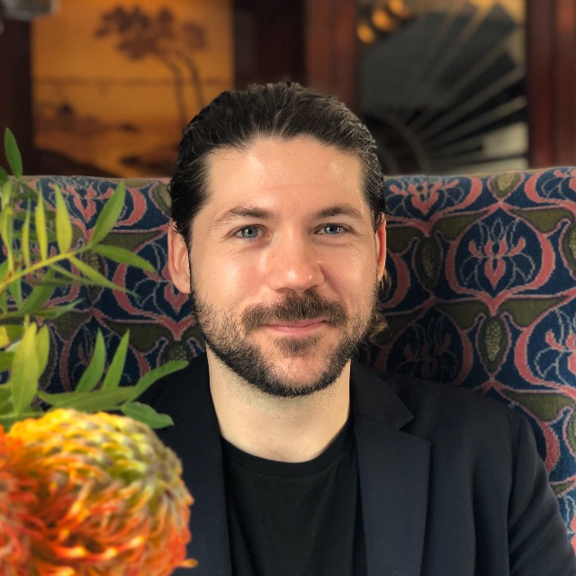 Joey seated in a restaurant, wearing a black jacket.